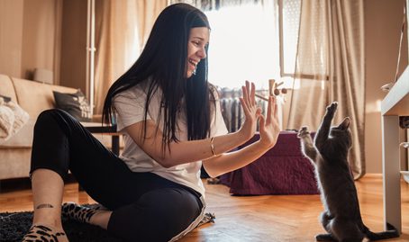 a woman high fiving a cat in a living room